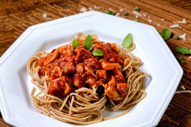 Domuz pastırmalı ve şampiyon soslu tam tahıllı spagetti fesleğenle süslenmiş ve yanında patates ekmeği ve vişneli domates..