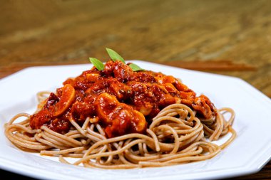 Domuz pastırmalı ve şampiyon soslu tam tahıllı spagetti fesleğenle süslenmiş ve yanında patates ekmeği ve vişneli domates..