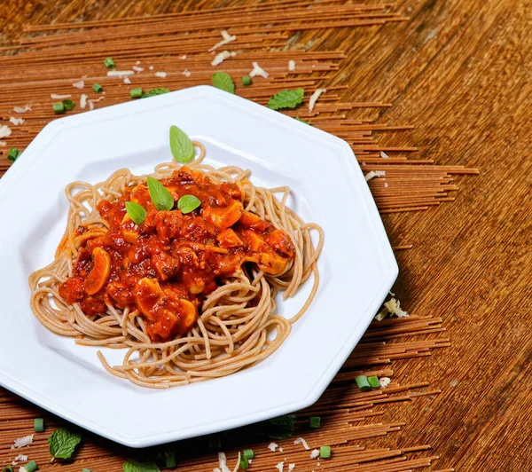 Domuz pastırmalı ve şampiyon soslu tam tahıllı spagetti fesleğenle süslenmiş ve yanında patates ekmeği ve vişneli domates..