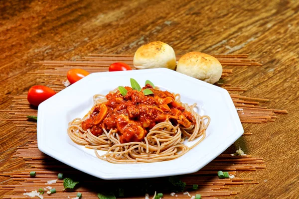 Domuz pastırmalı ve şampiyon soslu tam tahıllı spagetti fesleğenle süslenmiş ve yanında patates ekmeği ve vişneli domates..