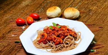 Domuz pastırmalı ve şampiyon soslu tam tahıllı spagetti fesleğenle süslenmiş ve yanında patates ekmeği ve vişneli domates..