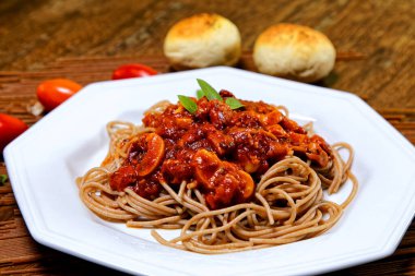 Domuz pastırmalı ve şampiyon soslu tam tahıllı spagetti fesleğenle süslenmiş ve yanında patates ekmeği ve vişneli domates..