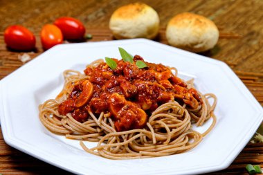 Domuz pastırmalı ve şampiyon soslu tam tahıllı spagetti fesleğenle süslenmiş ve yanında patates ekmeği ve vişneli domates..