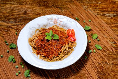 Bolonez soslu Fettuccine, fesleğen ve kiraz domatesleriyle süslenmiş, yanında kekik ekmeği..