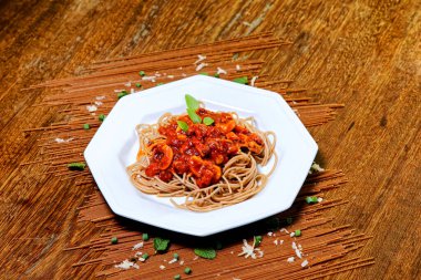 Domuz pastırmalı ve şampiyon soslu tam tahıllı spagetti fesleğenle süslenmiş ve yanında patates ekmeği ve vişneli domates..