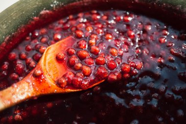 güneş tarafından aydınlatılmış bir tahta kaşıkla karıştırılmış çilek reçeli