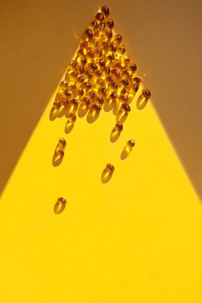 Vitamin D concept in the sunlight. Vitamin gelatin capsules in a ray of light. — Stock Photo, Image