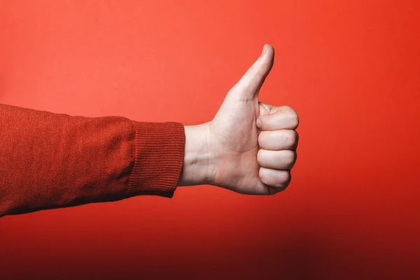 Man hand shows thumb up on red background