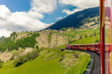 Kızıl tren İsviçre Alplerindeki Bernina Geçidi 'ne doğru yavaşça tırmanıyor. 