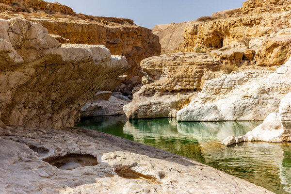 A stream of water in the rocky desert of Oman flowing in a canyo
