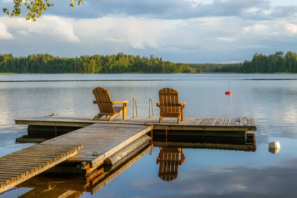 Two wooden chairs at Sunset on a pier on the shores of the calm — Stock Photo, Image