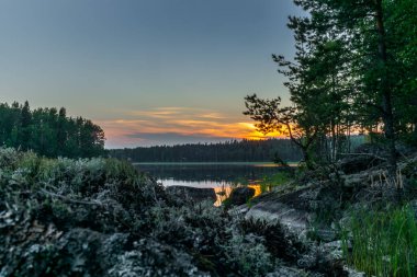 Finlandiya 'daki Kolovesi Ulusal Parkı' nda Saimaa gölünün sakin kıyılarında gün batımı