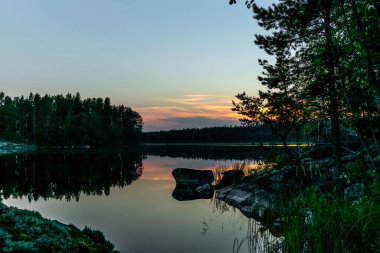Finlandiya 'daki Kolovesi Ulusal Parkı' nda Saimaa gölünün sakin kıyılarında gün batımı