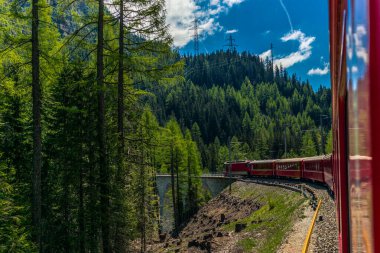 Kızıl tren İsviçre Alplerindeki Bernina Geçidi 'ne doğru yavaşça tırmanıyor.