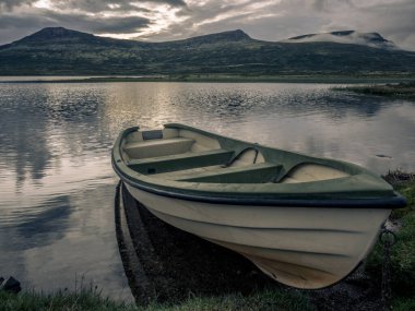 Norveç 'teki Rondane Ulusal Parkı' nda gün batımında gölde yalnız bir balıkçı teknesi.