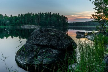 Finlandiya 'daki Kolovesi Ulusal Parkı' nda Saimaa gölünün sakin kıyılarında gün batımı