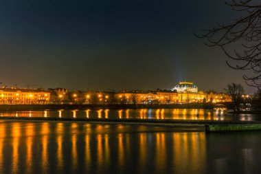 Prag 'daki Vltava Nehri' nin soğuk kış gecelerinde aydınlanan klasik binalar ve sokak ışıkları