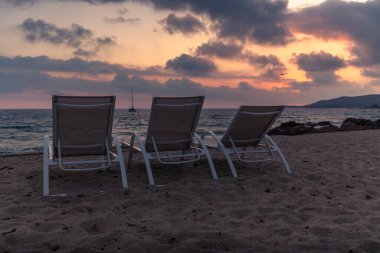 Gün batımında Korsika sahilinde şezlonglar.