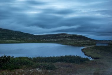Clouds reflecting on Norwegian lake at sunset in the Rondane National Park in Norway clipart