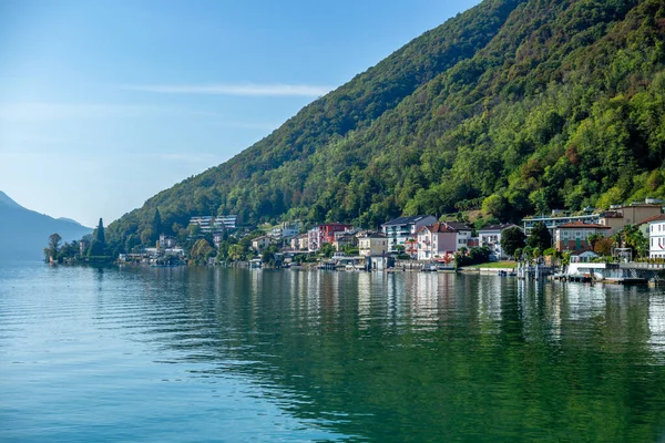 Sonbaharda güneşli bir günde Lugano Gölü kıyısındaki Melide köyünün manzarası.
