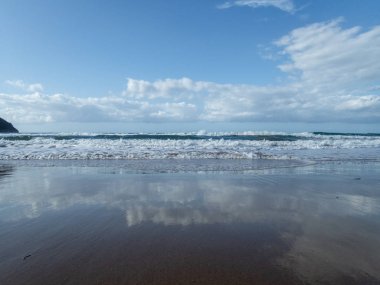 Dalgalar ve köpükler Toskana 'daki Baratti körfezinde kumsalda 