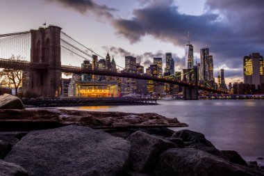 Gün batımında East River 'ın nehir kıyısından Brooklyn Köprüsü ve Manhattan manzarası  
