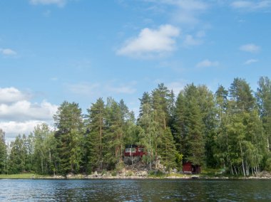 A typical scandinavian red wooden cottage on the shores of lake Saimaa in Finland 