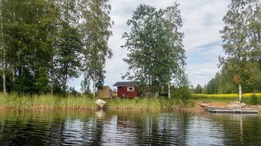 A typical Scandinavian red wooden cottage on the shores of lake Saimaa in Finland 