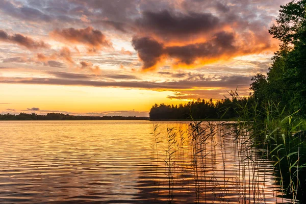 The shores of the calm Saimaa lake in Finland under a Nordic sky on fire