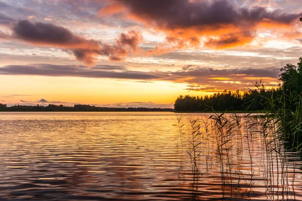 The shores of the calm Saimaa lake in Finland under a Nordic sky on fire