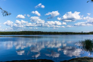Finlandiya 'daki Linnansaari Ulusal Parkı' ndaki Saimaa gölünün sakin sularını yansıtan beyaz bulutlar 