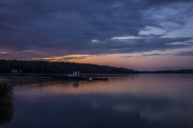 Finlandiya 'nın Porvoo kenti yakınlarındaki ahşap bir iskelede yaz günbatımında geleneksel bir cankurtaran ve kıyafet sığınağı değişimi.  