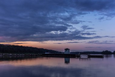 Finlandiya 'nın Porvoo kenti yakınlarındaki ahşap bir iskelede yaz günbatımında geleneksel bir cankurtaran ve kıyafet sığınağı değişimi.  