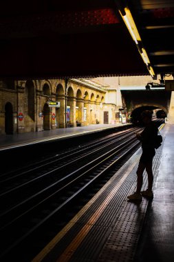 Londra, İngiltere - 23 Eylül 2019: İngiltere 'de bir tren istasyonunda trenini bekleyen genç bir kadın