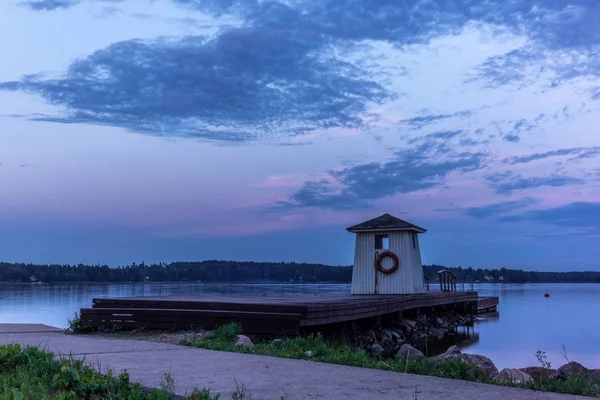 A traditional lifeguard and changing dress shelter on a wooden pier near the town of Porvoo in Finland at sunset in summer