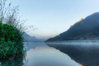 Güneş doğarken, Silvaplana Gölü 'ne yansıyan dağlar... Suyun üzerinde sis...