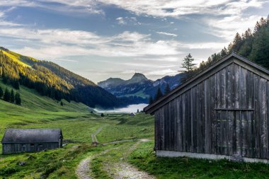 Saemtisersee gölüne giden yol sabahın erken saatlerinde sisle kaplıydı. Appenzell 'deki eski ahşap ahırlar ve kulübeler.