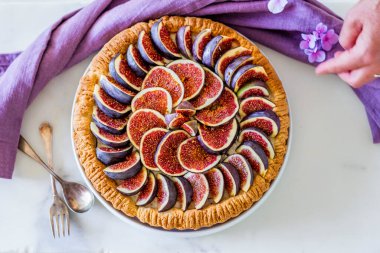 Mutfak masasında renkli incirli tart hazırlayan bir kadın.
