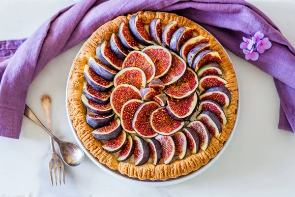 Mutfak masasında renkli incirli tart hazırlayan bir kadın.