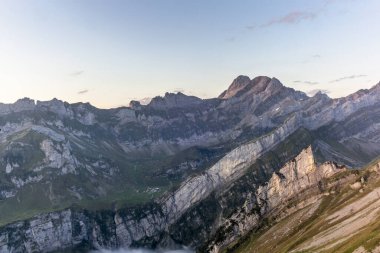 İsviçre 'nin Appenzell dağlarındaki görkemli Schaefler zirvesinin dik yamacında, Seealpsee vadisini kaplayan sisle birlikte renkli bir gün doğumu.