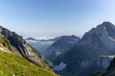 Appenzell, İsviçre 'deki Alpstein sıradağları. Vadide sis ve Seealpsee Gölü manzarası var.