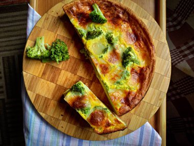 Brokoli ve tuzlu Suluguni peynirli sulu beyaz pastanın üst görüntüsü.