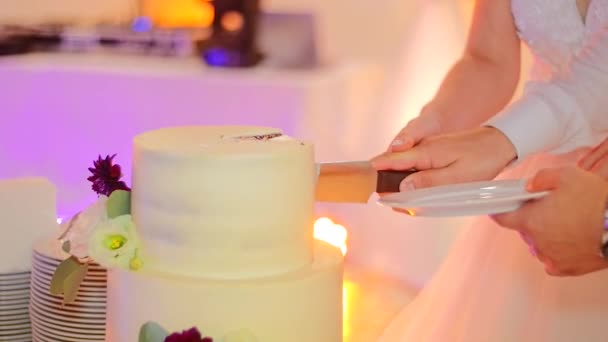 Les jeunes mariés ont coupé un beau gâteau de mariage décoré de fleurs . Clip Vidéo