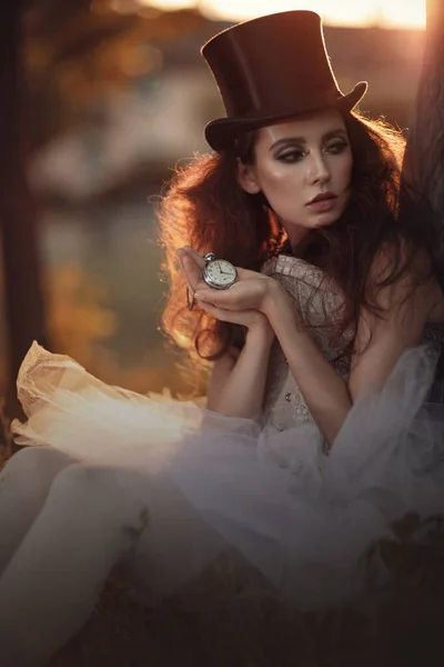 Hermosa morena en un sombrero negro vintage con un reloj en la mano . — Foto de Stock