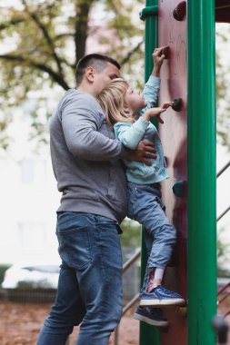 Küçük engelli kız oyun bahçesinde oynuyor.