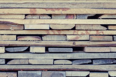 Katlanmış ahşap, kahverengi ve gri tahtalar. Birbiri üzerine istiflenmiş tahtalar. İnşaat için kereste.