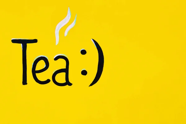 Té de inscripción con un sonriente escrito en tinta negra a mano sobre un fondo de madera amarillo. cafeterías, restaurantes — Foto de Stock