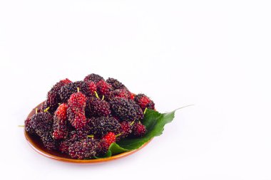 kırmızı ve kara dut meyvesi ve dut yaprağı kahverengi kâsede beyaz arka planda sağlıklı dut meyvesi izole edilmiş.