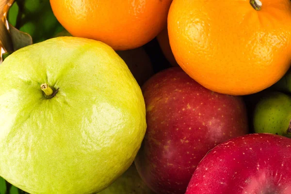 guava and orange and red apple are many fresh fruits mixed together on  background fruit health food