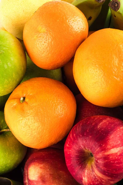 Arka plandaki meyvelerin üzerine sezonluk organik çiğ meyve (kırmızı elma ve muz ve portakal)